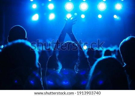 Concert silhouette of happy young woman partying on live event in crowded music hall.Curated shutterstock concert collection.Big group of young people partying on dance floor in night club. Royalty-Free Stock Photo #1913903740