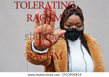 Tolerating racism is racism. African american woman, wear black face mask show stop hand sign. 
