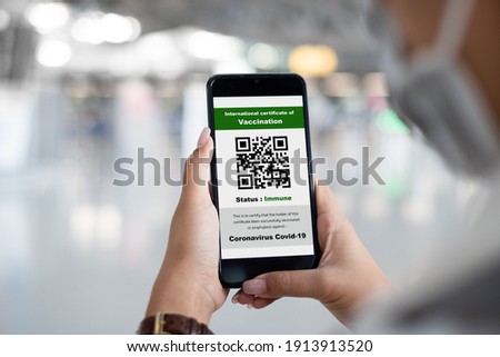 Traveler shows health passport of vaccination certification on phone at airport, to certicy that have been vaccinated of coronavirus covid-19 Royalty-Free Stock Photo #1913913520