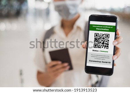 Traveler shows health passport of vaccination certification on phone at airport, to certicy that have been vaccinated of coronavirus covid-19 Royalty-Free Stock Photo #1913913523