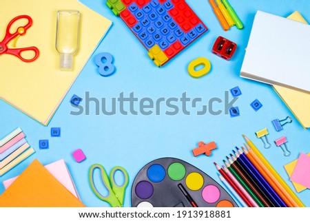 Farm with stationery accessories on blue background. Education and freelancer work concept. School supplies, pencils, paints, scissors, and colored books, on blue background with copy space.