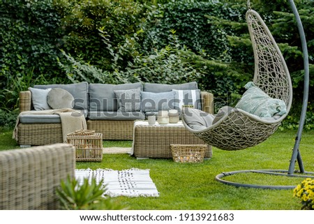 Comfortable wicker garden furniture with grey pillows in beautiful backyard Royalty-Free Stock Photo #1913921683