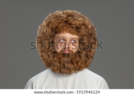 Half-length portrait of young very hairy man isolated over grey background. Royalty-Free Stock Photo #1913946124