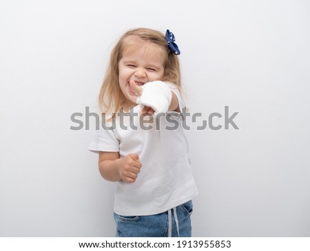 Little cute girl with hand in plaster showing the class on white background.