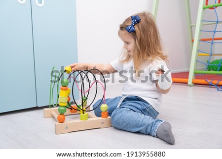 Little girl with hand in cast playing in wooden toys at home.