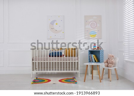 Cute baby room interior with comfortable crib and pictures