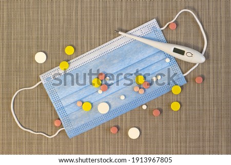 Blue mask and colorful pills on nice light textured background Narrow focus line, shallow depth of field