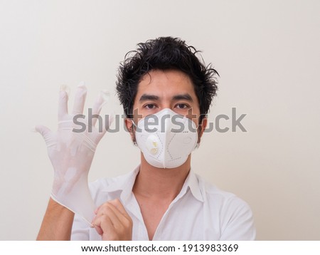 Confident man surgeon in medical mask on face wearing protective sterile glove on hand