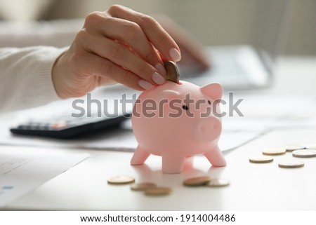 Close up woman holding smartphone, putting coin in pink piggy bank, young female browsing online banking service, planning budget, investment strategy, saving money, checking finances Royalty-Free Stock Photo #1914004486