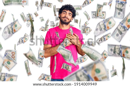 Handsome young man with curly hair and bear wearing casual pink tshirt smiling with hands on chest with closed eyes and grateful gesture on face. health concept.