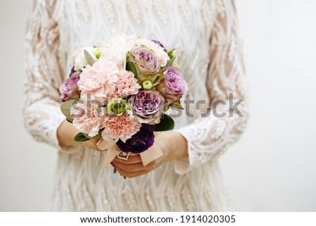 A selective focus of a beautiful flower bouquet on blurred background of a bride holding it
