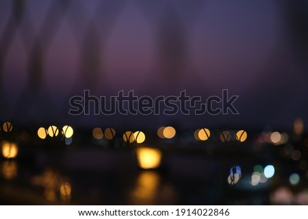 Defocused night of light city through grid, the sky are pink, blue and purple with yellow green blue and white bokeh.
