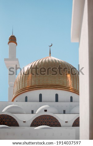 View of the dome and minaret through arch. Mosque architecture. Mosque design by Islamic religious architectural traditions. Kazakhstan, Central Asia. Creative abstract photography.