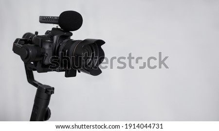 modern dslr camera on 3-axis gimbal stabilizer with microphone over gray background with copy space Royalty-Free Stock Photo #1914044731