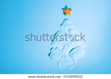 Christmas ice melting Christmas tree with star on blue background with copy space. 
