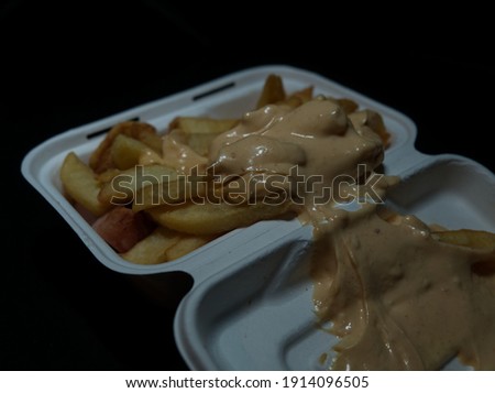 currywurst with fries into a cup. traditional german food to go with dip at corona times, negative space