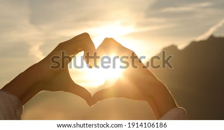 The hands of women and men are the heart shape with the sun light passing through the hands