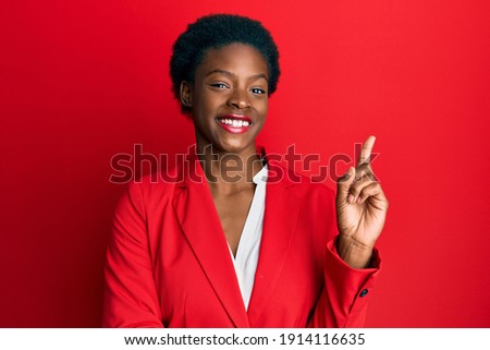 Young african american girl wearing business clothes with a big smile on face, pointing with hand and finger to the side looking at the camera. 