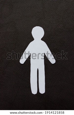Silhouette of a man of white paper, cut by hand. In the center of vertical photo on black background