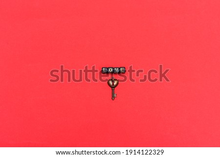 The inscription love is laid out with cubes with letters and a metal key in the form of a heart on a red background. A declaration of love.