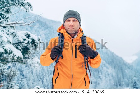 Man dressed bright orange softshell jacket with backpack have trekking on the winter mountains route. Active people or survival in the nature concept image. Royalty-Free Stock Photo #1914130669