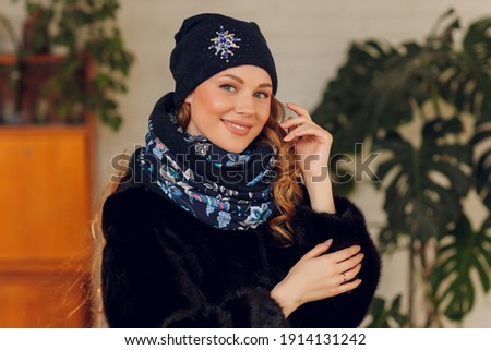happy beautiful woman looking sideways in excitement. girl wearing knitted warm hat and mittens.