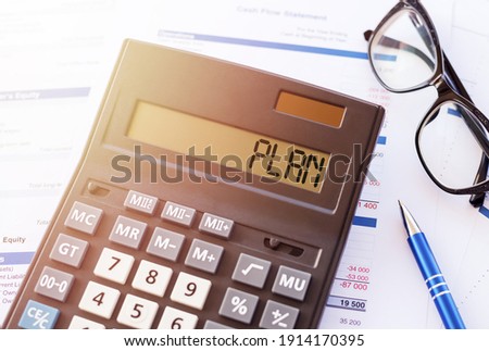 Word PLAN on the display of a calculator on financial documents.