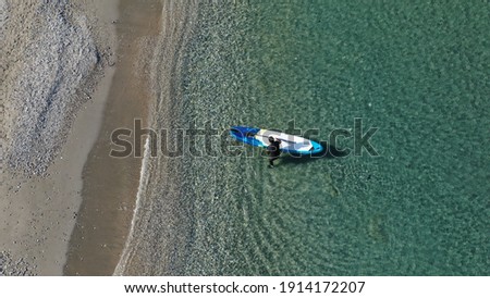 Aerial drone photo of fit man coming out of beach with his SUP or Stand Up Paddle board in tropical exotic emerald calm sea bay