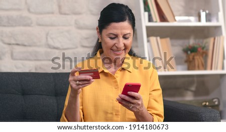 Elderly woman shopping online with credit card at home. Online banking with smart phone. Life style. Easy payment using a smartphone or digital device. Hands up