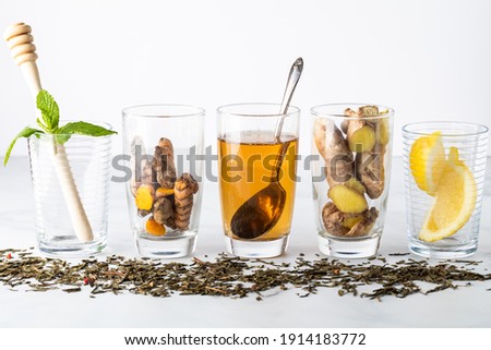 A row of small clear glasses filled with ingredients to make infused green tea. 