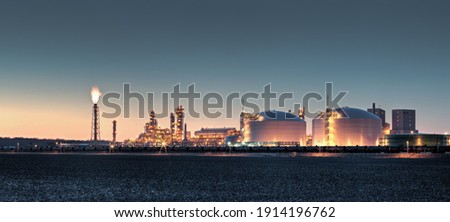 Fertilizer plant in an agricultural landscape at sunset. Railroad tanker cars stretched across the image. Night shot with lights on imposed on sunset background. Royalty-Free Stock Photo #1914196762