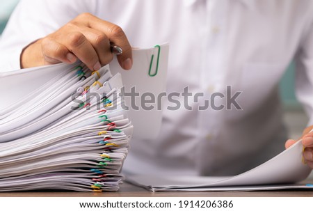 Business man or office workers with white shirt holding documents for writing on office desk, Stack of business overload paper.