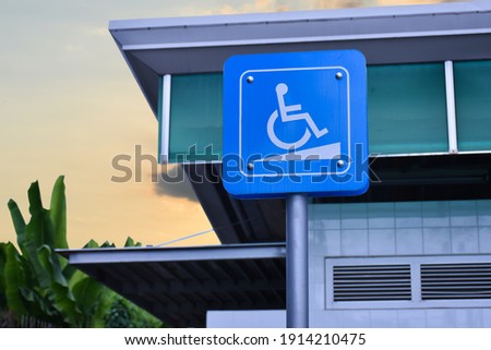 The wheelchair sign on pole with blue sky background.