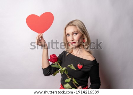 Girl holding a rose and a heart love symbol, Valentine's heart, on the floor hearts married space. inspiration. the event frame in the red dress girl, barefoot