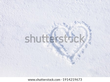 Top view, hand-drawn a heart shape on natural pure white soft snow surface in a cold weather day. Symbol of love in winter holiday season. Romantic outdoor concept for Valentine's day with copy space. Royalty-Free Stock Photo #1914219673