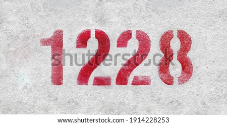 Red Number 1228 on the white wall. Spray paint.