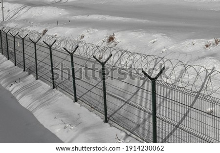 Sharp razor wire on mesh fence. Basic fences for objects of the penitentiary system, border control, prison, restricted area. Winter time scene