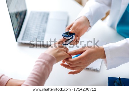 Close up photo of oxygen pressure measurement. Female hands of a doctor and patient. Doctor uses a pulse oximeter to measure the patient's pulse and oxygen level Royalty-Free Stock Photo #1914238912