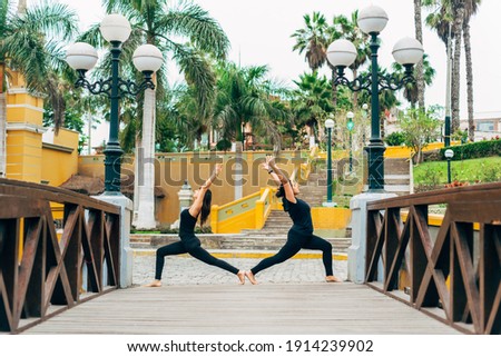 Women practicing the warrior pose in a traditional outdoor setting