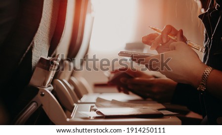 Tourist hand filling Immigration form on flight to visit country. A man is writing, signing on a paper.Man passenger Write Immigration Card in Airplane
