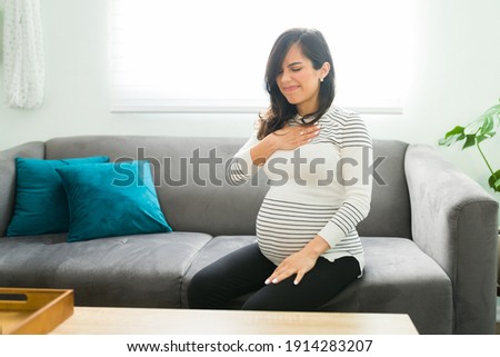 Pretty pregnant woman suffering from acid reflux because of her pregnancy. Caucasian expectant mother touching her chest with a pained expression Royalty-Free Stock Photo #1914283207