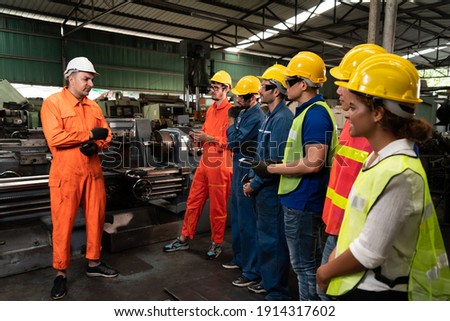Skillful worker attending brief meeting in the factory . Industrial people and manufacturing labor concept . Royalty-Free Stock Photo #1914317602