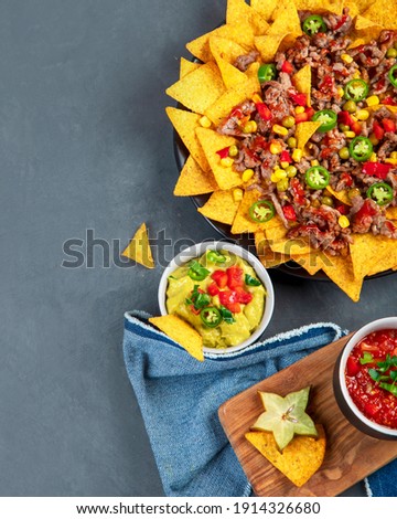 Delicious hispanic mexican meal board with nachos, beef, guacamole, avocado and starfruit. Hot and spicy. Top view, copy space