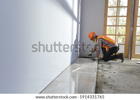 Laying Ceramic Tiles.Home tile improvement - handyman with level.Tiler works with flooring