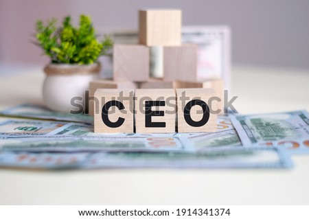 Dollars banknote with calculator and word CEO. Banknotes and wooden cubes with letters. CEO concept with wooden blocks. CEO - short for Chief Executive Officer.
