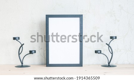 Mockup of a frame for a photo with candle sticks on a wooden table. 