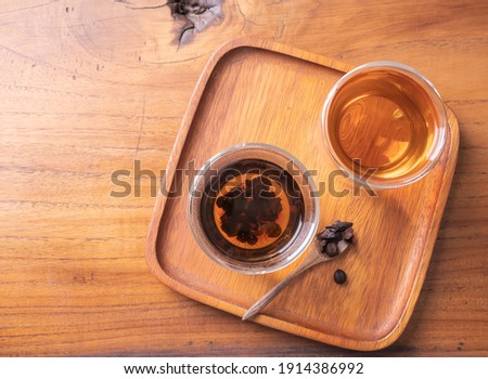 Cascara tea  glass cup on  natural teak wood table  background,top view