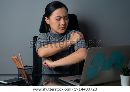 Asian woman working on a laptop was sick with body pain sitting at office. isolated on gray background.