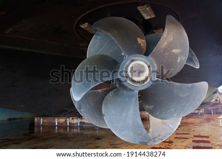 The bottom of a ship supported in dry dock with azimuth propulsion and twin propellers aft. Royalty-Free Stock Photo #1914438274