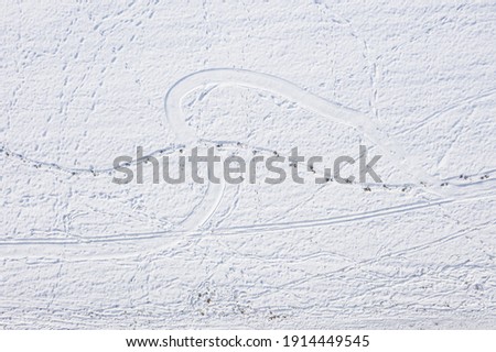 Snow covered winter landscape in Bavarian forest with traces of car tires sled footprints in deep snow, Germany